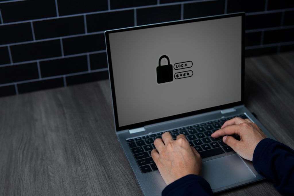 A close-up image of a person's hands typing a password on a laptop